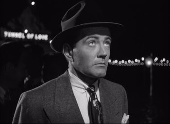 Movie still from “Strangers on a Train” (1951), directed by Alfred Hitchcock – A man wearing a suit and a hat; Close Up shot, Low angle