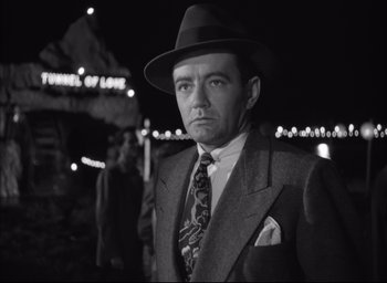 Movie still from “Strangers on a Train” (1951), directed by Alfred Hitchcock – A black and white photo of a man wearing a suit and hat; Close Up shot, Low angle