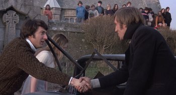 Movie still from “Straw Dogs” (1971), directed by Sam Peckinpah – A man and woman shaking hands in front of a crowd; Medium shot, Over the shoulder angle