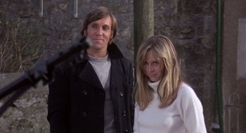 Movie still from “Straw Dogs” (1971), directed by Sam Peckinpah – A man and a woman standing next to each other in front of a brick wall; Medium shot, Low angle