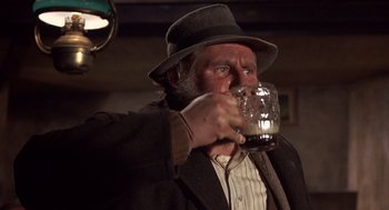 Movie still from “Straw Dogs” (1971), directed by Sam Peckinpah – An older man drinking a glass of water; Close Up shot, Low angle