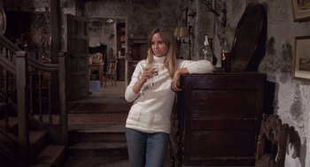 Movie still from “Straw Dogs” (1971), directed by Sam Peckinpah – A woman in a white sweater leaning on a wall holding a cup; Medium shot, Low angle