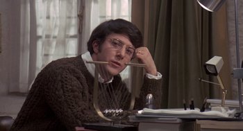 Movie still from “Straw Dogs” (1971), directed by Sam Peckinpah – A man sitting at a table with a harp; Medium shot, Low angle