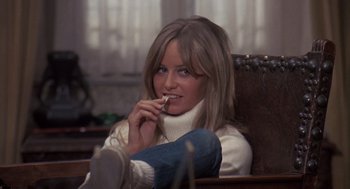 Movie still from “Straw Dogs” (1971), directed by Sam Peckinpah – A woman sitting in a chair eating a piece of food; Close Up shot, High angle