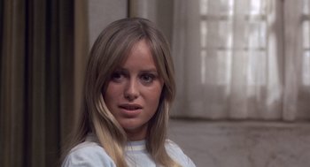 Movie still from “Straw Dogs” (1971), directed by Sam Peckinpah – A woman with long blonde hair sitting in front of a window; Close Up shot, Low angle