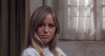 Movie still from “Straw Dogs” (1971), directed by Sam Peckinpah – A woman with long blonde hair sitting in front of a window; Close Up shot, Low angle