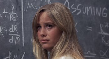 Movie still from “Straw Dogs” (1971), directed by Sam Peckinpah – A young woman with long blonde hair standing in front of a chalkboard; Close Up shot, High angle