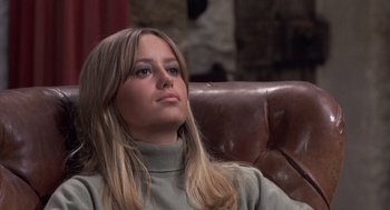 Movie still from “Straw Dogs” (1971), directed by Sam Peckinpah – A beautiful young lady sitting on a brown leather chair; Close Up shot, Low angle