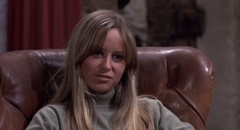 Movie still from “Straw Dogs” (1971), directed by Sam Peckinpah – A woman sitting on a leather couch in a room; Close Up shot, High angle