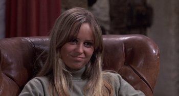 Movie still from “Straw Dogs” (1971), directed by Sam Peckinpah – A woman sitting on a brown leather couch; Close Up shot, Over the shoulder angle