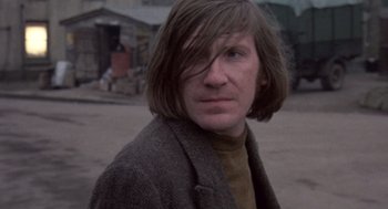 Movie still from “Straw Dogs” (1971), directed by Sam Peckinpah – A man with long brown hair wearing a brown jacket; Close Up shot, Low angle