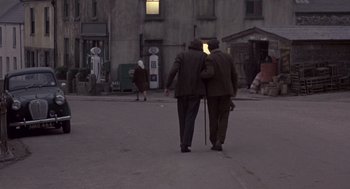 Movie still from “Straw Dogs” (1971), directed by Sam Peckinpah – Two men walking down the street in front of a building; Wide shot, High angle