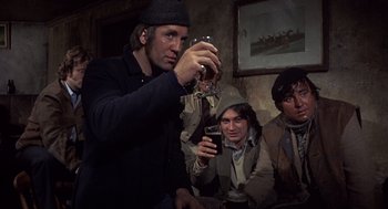 Movie still from “Straw Dogs” (1971), directed by Sam Peckinpah – A group of men sitting around a table drinking wine; Medium shot, Low angle