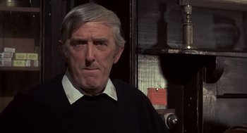Movie still from “Straw Dogs” (1971), directed by Sam Peckinpah – An older man in a black shirt and white shirt; Close Up shot, Over the shoulder angle