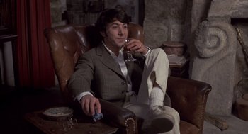 Movie still from “Straw Dogs” (1971), directed by Sam Peckinpah – A man sitting in a chair holding a glass of wine; Medium shot, High angle
