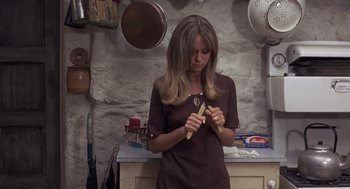 Movie still from “Straw Dogs” (1971), directed by Sam Peckinpah – A woman holding a banana in a kitchen; Medium shot, High angle