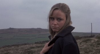 Movie still from “Straw Dogs” (1971), directed by Sam Peckinpah – A woman in a black jacket standing in a field; Close Up shot, Low angle