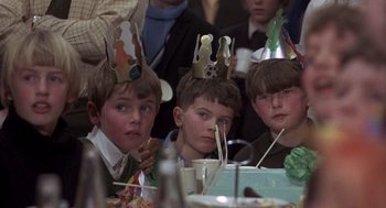 Movie still from “Straw Dogs” (1971), directed by Sam Peckinpah – A group of young boys sitting at a table wearing party hats; Close Up shot, High angle