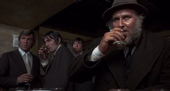 Movie still from “Straw Dogs” (1971), directed by Sam Peckinpah – A group of men standing next to each other in a room; Close Up shot, Low angle