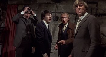Movie still from “Straw Dogs” (1971), directed by Sam Peckinpah – A group of men standing next to each other in suits; Medium shot, High angle