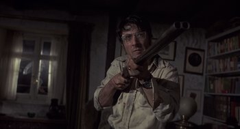 Movie still from “Straw Dogs” (1971), directed by Sam Peckinpah – A man holding a gun while wearing safety glasses; Close Up shot, Low angle