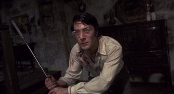 Movie still from “Straw Dogs” (1971), directed by Sam Peckinpah – A man with a knife sitting in a room; Close Up shot, Low angle