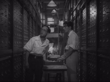 Movie still from “Stray Dog” (1949), directed by Akira Kurosawa – Two men standing next to each other in a room; Medium shot, Low angle