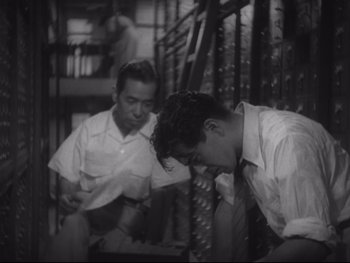 Movie still from “Stray Dog” (1949), directed by Akira Kurosawa – Two young men sitting next to each other on stairs; Medium shot, Low angle