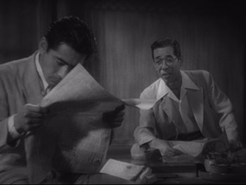 Movie still from “Stray Dog” (1949), directed by Akira Kurosawa – Two men are sitting at a table and one of them is reading a newspaper; Medium shot, Low angle