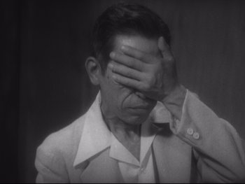 Movie still from “Stray Dog” (1949), directed by Akira Kurosawa – An old photo of a man covering his face with his hands; Close Up shot, High angle