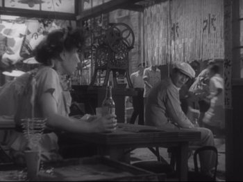 Movie still from “Stray Dog” (1949), directed by Akira Kurosawa – A group of people sitting at a table with drinks; Medium shot, High angle