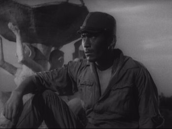 Movie still from “Stray Dog” (1949), directed by Akira Kurosawa – A black and white photo of a man sitting on the ground with an umbrella; Medium shot, Low angle