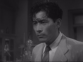 Movie still from “Stray Dog” (1949), directed by Akira Kurosawa – A man wearing a suit and tie in front of a mirror; Close Up shot, Low angle