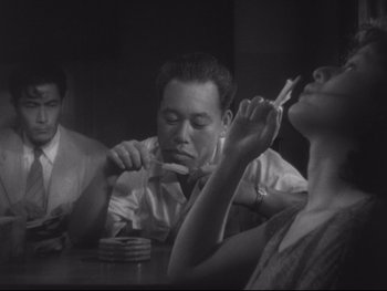 Movie still from “Stray Dog” (1949), directed by Akira Kurosawa – A man and a woman sitting at a dinner table; Medium shot, Low angle