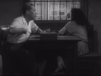 Movie still from “Stray Dog” (1949), directed by Akira Kurosawa – A man and a woman sitting at a table in front of each other; Medium shot, High angle