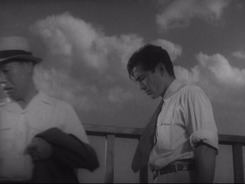 Movie still from “Stray Dog” (1949), directed by Akira Kurosawa – A man wearing a tie standing next to another man wearing a tie; Medium shot, Low angle