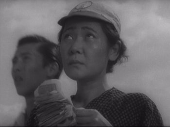 Movie still from “Stray Dog” (1949), directed by Akira Kurosawa – An old photo of a woman holding a stack of papers; Close Up shot, Low angle