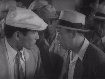 Movie still from “Stray Dog” (1949), directed by Akira Kurosawa – A group of men standing next to each other in a room; Medium shot, High angle