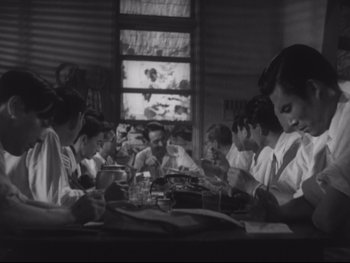 Movie still from “Stray Dog” (1949), directed by Akira Kurosawa – A black and white photo of a group of people sitting at a table; Medium shot, High angle