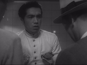 Movie still from “Stray Dog” (1949), directed by Akira Kurosawa – A man wearing a white jacket is looking at another man in a hat; Close Up shot, Over the shoulder angle