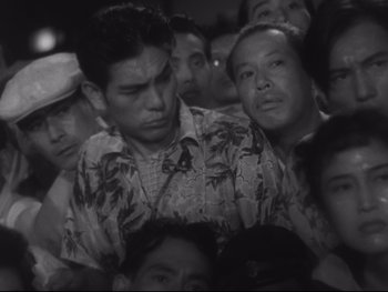 Movie still from “Stray Dog” (1949), directed by Akira Kurosawa – A black and white photo of a group of people; Medium shot, High angle