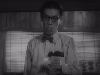 Movie still from “Stray Dog” (1949), directed by Akira Kurosawa – A black and white photo of a man holding a mustache; Close Up shot, Low angle