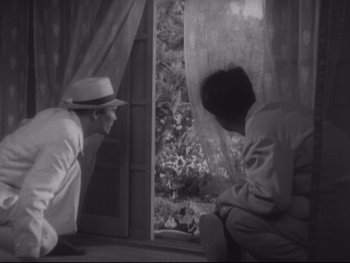 Movie still from “Stray Dog” (1949), directed by Akira Kurosawa – A man and a woman sitting in front of a window; Medium shot, High angle