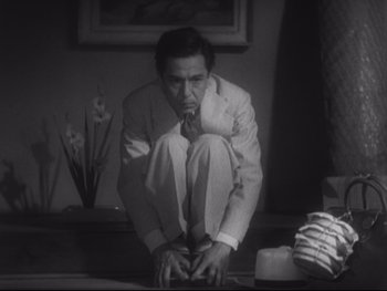 Movie still from “Stray Dog” (1949), directed by Akira Kurosawa – A black and white photo of a man in a suit and tie; Medium shot, Low angle