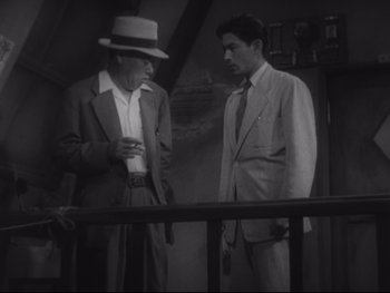 Movie still from “Stray Dog” (1949), directed by Akira Kurosawa – Two men standing next to a railing in a room; Medium shot, High angle