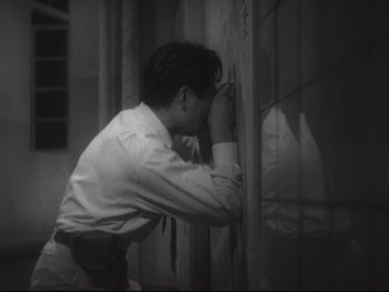 Movie still from “Stray Dog” (1949), directed by Akira Kurosawa – A man leaning against a wall with his hand on his face; Medium shot, High angle