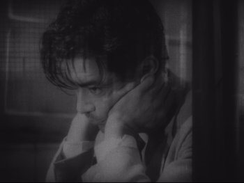 Movie still from “Stray Dog” (1949), directed by Akira Kurosawa – A black and white photo of a man leaning on a wall; Close Up shot, High angle
