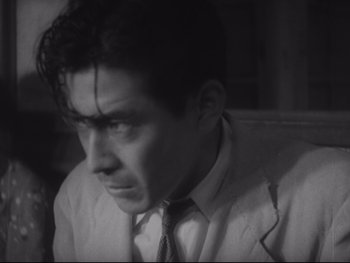 Movie still from “Stray Dog” (1949), directed by Akira Kurosawa – A black and white photo of a man in a suit and tie; Close Up shot, Low angle