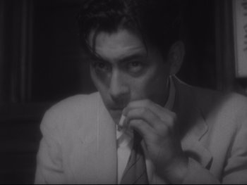 Movie still from “Stray Dog” (1949), directed by Akira Kurosawa – A black and white photo of a man in a suit; Close Up shot, High angle