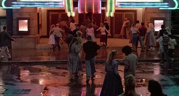 Movie still from “Streets of Fire” (1984), directed by Walter Hill – A group of people standing on a wet sidewalk; Extreme Wide shot, High angle